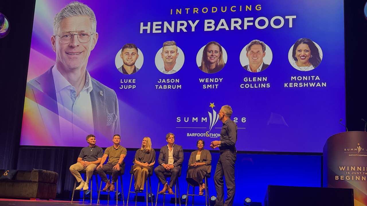 Five Barfoot & Thompson panellists seated on stage in front of a screen introducing Henry Barfoot