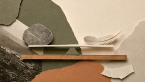 Hand-cut paper collage of a level seesaw balancing a stone and a feather on a wooden ruler, in earthy olive and clay tones