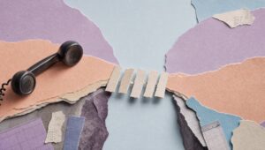 Hand-cut paper collage of a small paper footbridge crossing a torn paper gap, with a vintage telephone handset
